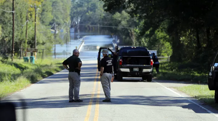 FILE - In this Sept. 19, 2018, file photo, responders congregate near where two people drowned the evening before when they were locked in a Horry County Sheriff's department transport van while crossing an overtopped bridge over the Little Pee Dee River on Highway 76, during rising floodwaters in the aftermath of Hurricane Florence in Marion County, S.C. The estates of the South Carolina women who drowned filed lawsuits last week in Horry County alleging negligence by a company that created policies and p…