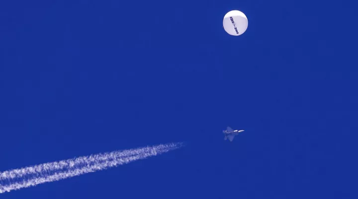 A fighter jet flies near a large balloon drifting above the Atlantic Ocean, just off the coast of South Carolina near Myrtle Beach, Saturday, Feb. 4, 2023. Minutes later, the balloon was struck by a missile from an F-22 fighter jet, ending its weeklong traverse over the U.S. China said the balloon was a weather research vessel blown off course, a claim rejected by U.S. officials. (Chad Fish via AP)
