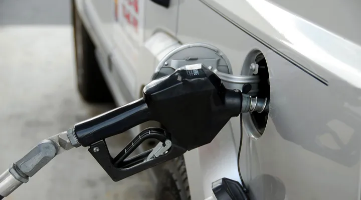 A nozzle filling up a vehicle with gas