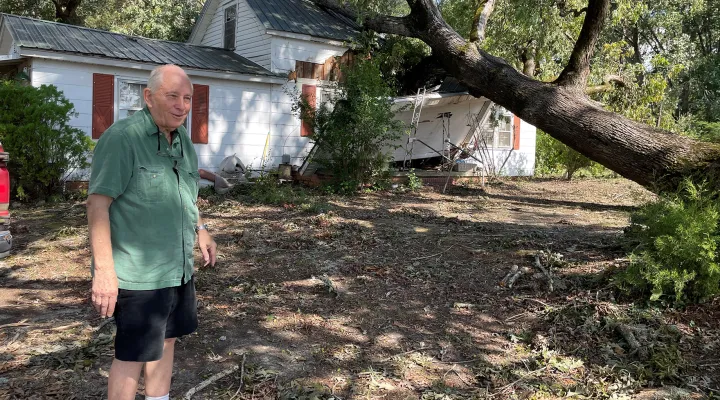 Eddie Coleman stands beside his house in Greenwood County Monday. He has a bruise on top of his head where his living room ceiling caved in under the weight of the tree.