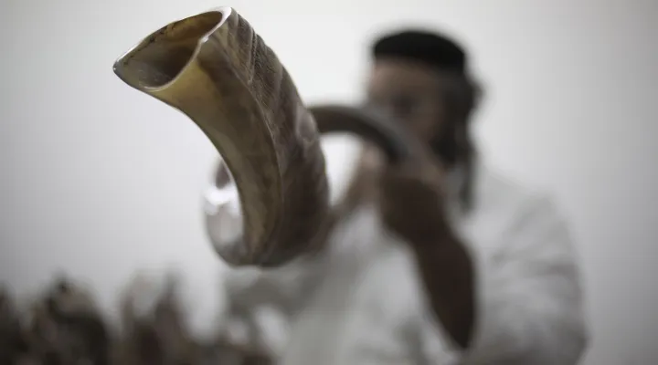 In this Monday, Sept. 22, 2014 photo, Moshe Manos tests a shofar, or ram's horn, before purchasing one at a workshop that produces them in Tel Aviv, Israel. A shofar is traditionally used during the Jewish New Year holiday of Rosh Hashana which starts at sundown on Wednesday.