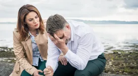 A woman comforts a grieving man