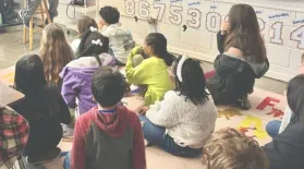 photo of students sitting on classroom floor